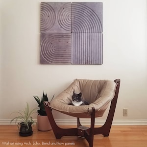 May include: A gray and white cat sits in a brown leather chair in front of a wall with four gray geometric wall art panels. The wall art panels are made of wood and have a raised design. The text "Wall art using Arch, Echo, Bend and Row panels" is at the bottom of the image.