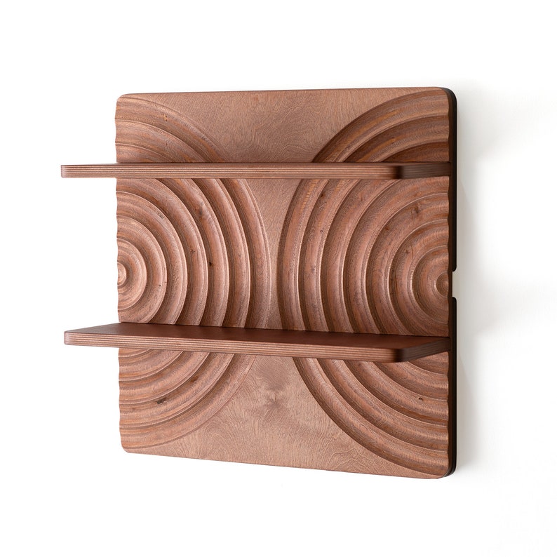 May include: A wooden wall shelf with two shelves. The shelf has a unique design with concentric circles carved into the wood. The shelf is a dark brown color.