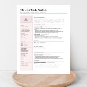 Op de afbeelding: Een cv-sjabloon met een roze accentkleur, met secties voor contactgegevens, professionele samenvatting, ervaring, opleiding en vaardigheden. Het cv wordt weergegeven op een houten dienblad.