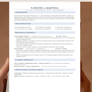 May include: A resume for Nathaniel A. Hartwell, a Senior Business Strategist. The document lists career highlights, core competencies, professional experience, academic credentials, and certifications. The resume is printed on white paper with black text.
