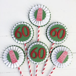 May include: Six green and white paper cupcake toppers with red glitter numbers "60" and a red and white illustration of the Leaning Tower of Pisa.