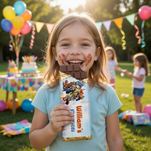 May include: A young girl smiles, chocolate smeared on her face, holding a partially eaten chocolate bar. The bar's wrapper features cartoon characters and the text "William's 8th Birthday". A party with balloons and a cake is in the background.