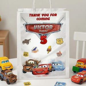 Pu&ograve; includere: Borsa regalo bianca con personaggi del film Cars e la scritta "Thank You For Coming". La borsa &egrave; decorata con il nome "Victor" e il numero "5". Le macchinine giocattolo sono posizionate intorno alla borsa.