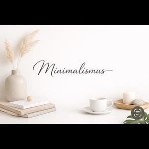 Könnte beinhalten: Ein minimalistisches Stillleben mit einer beigen Vase mit getrocknetem Pampasgras, gestapelten Büchern, einem kleinen Holztablett mit einer Kerze und einem Stein sowie einer weißen Tasse und Untertasse. Das Wort "Minimalismus" ist kursiv geschrieben.