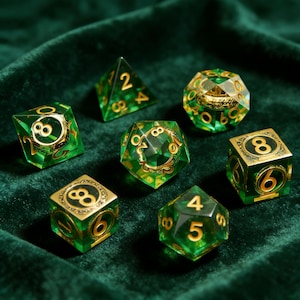 Puede incluir: Juego de siete dados poliédricos en tonos verdes con numeración y detalles dorados. Los dados se muestran sobre una superficie de terciopelo verde oscuro. Los dados son para juegos de rol.