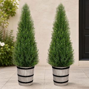 May include: Two artificial cone-shaped evergreen trees with dense green foliage. Each tree is planted in a cylindrical grey wooden barrel-style planter featuring three distinct black horizontal bands around the exterior of the container.