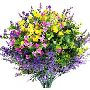 以下が含まれることがあります： 鮮やかな色の人工花のブーケ。黄色、ピンク、紫、緑の葉が含まれています。花は密集しており、ふっくらとした質感があり、家の装飾に最適です。
