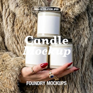 May include: Three candle jars with black lids and blank white labels are stacked. The jars are held in front of a fur coat. The image includes the text "Candle Mockup" and "FOUNDRY MOCKUPS".
