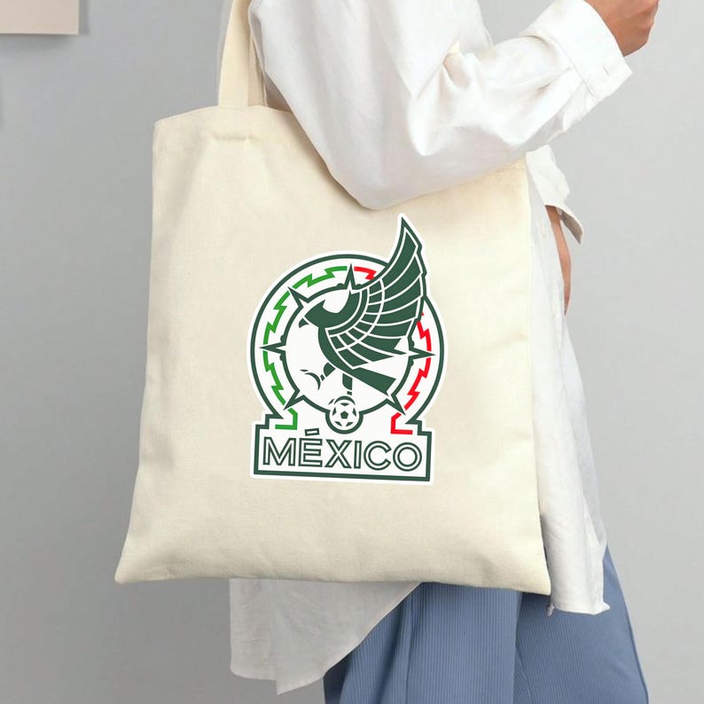 Peut inclure: Sac fourre-tout cr&egrave;me avec l'embl&egrave;me national mexicain en vert, rouge et blanc. L'embl&egrave;me comprend un aigle avec un serpent, un ballon de football et le mot "M&eacute;xico". Le sac est port&eacute; par une personne v&ecirc;tue d'une chemise blanche et d'un pantalon bleu.