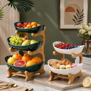 Peut inclure: Un présentoir à fruits à trois niveaux en céramique vert foncé rempli de tomates, raisins, poires, oranges et pamplemousse, à côté d'un présentoir à deux niveaux blanc contenant des fraises, myrtilles, biscuits, croissant et macarons.