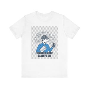 May include: White t-shirt featuring a blue graphic of an engineer with a hard hat, blueprints, and a calculator. The text "ENGINEER MODE: ALWAYS ON" is below the graphic. The shirt is made of a soft, comfortable material.