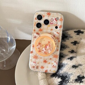 K&ouml;nnte beinhalten: Transparente Handyh&uuml;lle mit Hello Kitty-Design, Ahornbl&auml;ttern und einem Pop-up-Griff. Die H&uuml;lle hat ein hellbeige kariertes Muster und einen transparenten Griff mit schwebendem Konfetti. F&uuml;r ein Smartphone.