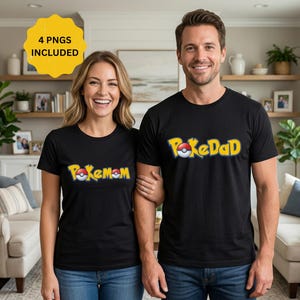 Puede incluir: Dos personas vestidas con camisetas negras con texto amarillo y blanco. Una camiseta dice "PokeMom" y la otra "PokeDad". Las camisetas son de manga corta y el texto está en una fuente estilizada. El fondo incluye un salón.