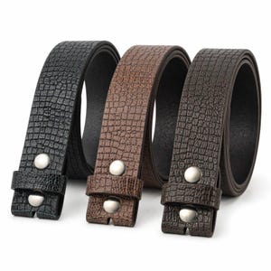 Pode incluir: Três cintos nas cores preto, castanho-claro e castanho-escuro, cada um com um padrão texturizado de relevo de crocodilo. Cada cinto inclui uma presilha a condizer e dois botões de pressão de metal prateado na extremidade, com design uniforme.