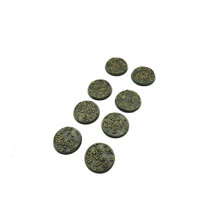 May include: A collection of eight small, round, textured bases. The bases are painted in shades of green and brown, with a mottled, organic appearance. They are likely designed for miniature figures or models.