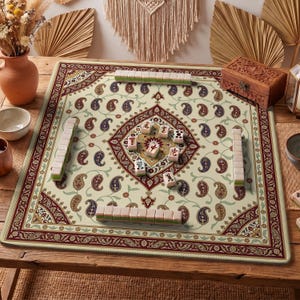 Puede incluir: Un juego de Mahjong sobre una alfombra beige con un estampado de cachemira en rojo, verde y azul. El juego incluye fichas y una caja de madera. El juego está sobre una mesa de madera con objetos decorativos en el fondo.