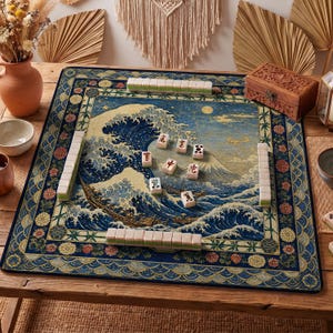 Könnte beinhalten: Ein Mahjong-Spielset auf einem Holztisch. Das Spielbrett zeigt ein blau-weißes Wellenmuster mit einem Berg im Hintergrund. Das Set enthält Spielsteine und eine Holzkiste. Das Brett ist von einem floralen Rand umgeben.