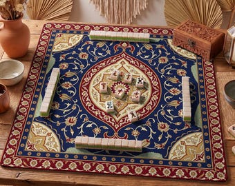 May include: A blue Mahjong game mat with a floral design and red border. The mat is set on a wooden table and features several stacks of tiles. A wooden box and vase are also visible.