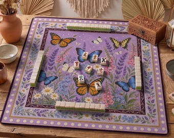 May include: A Mahjong game set on a purple mat with a floral and butterfly design. The mat features a border of white dots and a decorative edge. The set includes tiles and a wooden box. The game is set on a wooden table.