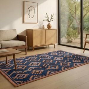 May include: A rectangular, navy blue rug with a geometric pattern in a light brown color. The rug is placed on a light wood floor in a living room setting. A wooden sofa, coffee table, and cabinet are also visible.