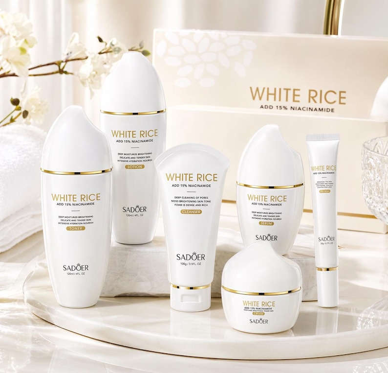 May include: A collection of white skincare products with gold accents, including bottles, tubes, and a jar. The products are labeled "WHITE RICE ADD 15% NIACINAMIDE" and "SADOER". The set includes toner, lotion, cleanser, serum, and cream.