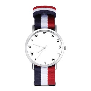 May include: A silver wristwatch with a white face and Hebrew numerals. The watch has a striped band in red, white, and navy blue. The watch hands are silver. The watch band is approximately 0.75 inches wide.
