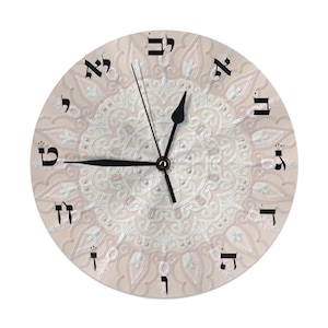 May include: Circular wall clock featuring a beige backdrop with a white floral pattern. Black Hebrew numerals indicate the hours. The clock hands are black. A decorative item for the home.