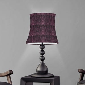 May include: A black table lamp with a dark purple patterned lampshade. The lamp has a round base and a tall, slender stem with three decorative balls.