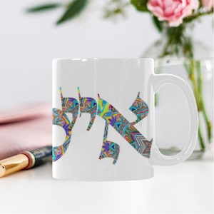 May include: White ceramic mug with a colorful Hebrew word design. The word is written in a stylized font with a geometric pattern.