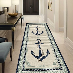 May include: A rectangular nautical-themed rug with a cream-colored background and a navy blue border. The rug features two navy blue anchors with rope detailing. The border includes a light blue and navy blue design.