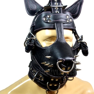 Peut inclure: Capuche de chiot en cuir noir avec coutures roses, clous en métal et anneaux argentés. La capuche comporte des oreilles attachées et un museau avec des pointes métalliques. Un collier assorti est également inclus.
