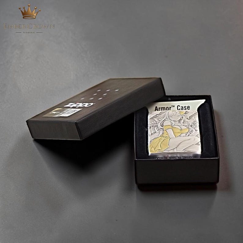 Puede incluir: Un encendedor Armor Case plateado con una ilustraci&oacute;n de estilo anime amarillo y blanco, presentado en una caja negra. La caja est&aacute; abierta, revelando el encendedor y su estuche protector. El encendedor presenta el texto "Armor Case".