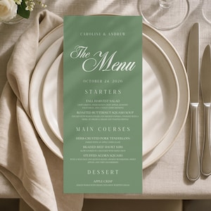 May include: A sage green rectangular menu card featuring white text that reads Caroline & Andrew, The Menu, October 24, 2026, Starters, Fall Harvest Salad, Roasted Butternut Squash Soup, Main Courses, Herb-Crusted Pork Tenderloin, Braised Beef Short Ribs, Stuffed Acorn Squash, Dessert, and Apple Crisp.