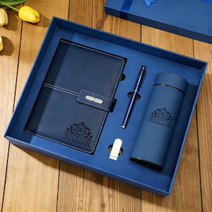 May include: A navy blue gift set comprising a notebook, pen, and tumbler, each bearing the name "WILLIAM" and a decorative emblem. Presented in a blue box with a matching lid, suitable for gifting.