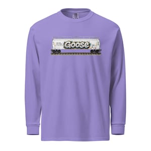May include: A long-sleeve, lilac-colored shirt featuring a graphic of a white train car with the word "Goose" in graffiti-style lettering. The train car graphic includes details like train tracks and text.