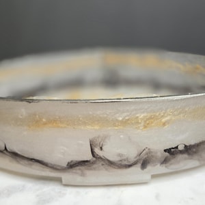 Puede incluir: Una taza de cerámica blanca con un asa negra y el texto "But First, Coffee" en un estilo manuscrito. La taza está sobre una superficie blanca. La taza mide 10 cm de alto.