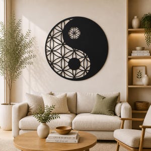 Può includere: Una grande opera d'arte da parete Yin e Yang in metallo nero. Il design presenta un motivo floreale ritagliato nella parte chiara del simbolo. L'opera d'arte è montata su una parete di colore neutro sopra un divano.