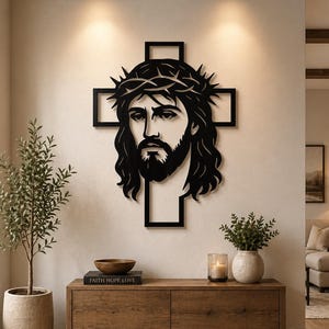 Könnte beinhalten: Ein schwarzes Metall-Wandkunstwerk, das ein stilisiertes Bild von Jesus mit einer Dornenkrone vor einem kreuzförmigen Hintergrund darstellt. Das Kunstwerk ist an einer neutralfarbenen Wand angebracht und erzeugt einen auffälligen Kontrast. Es ist ein religiöses Wohnaccessoire.