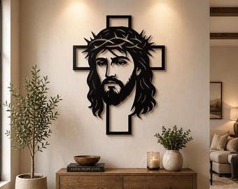 May include: A black metal wall art piece depicting a stylized image of Jesus wearing a crown of thorns, set against a cross-shaped background. The artwork is mounted on a neutral-colored wall, creating a striking contrast. The piece is a religious home decor item.