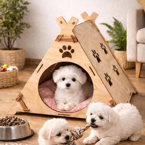 May include: A wooden dog teepee with paw print cutouts, sheltering a small white dog on a pink cushion. Two white puppies play with a rope toy nearby. A bowl of dog food and toys are also visible.