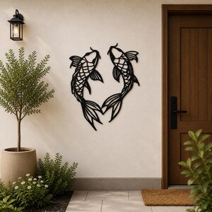 Pode incluir: Arte de parede em metal preto com dois peixes koi voltados um para o outro, formando um coração. Os peixes têm escamas detalhadas e barbatanas fluidas. A obra de arte é montada em uma parede clara perto de uma porta e vegetação.