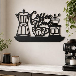 May include: A black metal wall art piece featuring the text "Coffee Time" in a script font, accompanied by silhouettes of a moka pot, a coffee cup with a geometric pattern, and a manual coffee grinder, all resting on a horizontal base line.