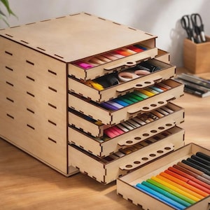 Puede incluir: Un organizador de escritorio de madera con múltiples cajones, llenos de útiles de arte coloridos. El organizador es de madera clara y tiene forma rectangular. Los cajones están abiertos, revelando bolígrafos, lápices y tijeras.