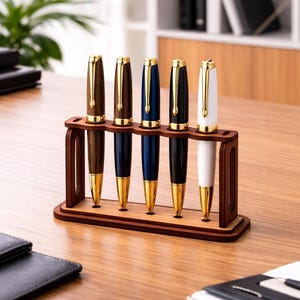 May include: A wooden pen holder with five pens. The pens have gold accents and are in various colors: brown, navy, dark blue, black, and white. The holder is made of dark brown wood and sits on a wooden desk.