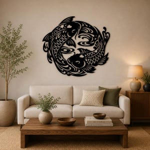 Pode incluir: Arte de parede em metal preto retratando dois peixes koi em um design circular, formando um símbolo yin e yang. Os peixes são estilizados com detalhes intrincados. A obra de arte é montada em uma parede neutra acima de um sofá.