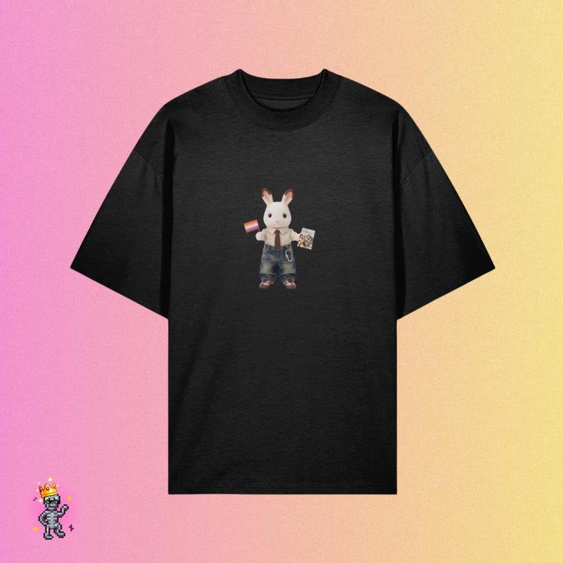 Puede incluir: Una camiseta negra de manga corta con un gr&aacute;fico central de un conejo blanco que viste una camisa beige, una corbata marr&oacute;n y un peto de mezclilla azul. El conejo sostiene una peque&ntilde;a bandera rectangular con rayas y un peque&ntilde;o libro.