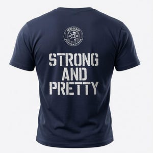 May include: A navy blue short-sleeve t-shirt featuring a white circular logo at the top center with the text SEND SLACK and SPECIALISM IN THE ENDURO. Below the logo, the words STRONG AND PRETTY are printed in a distressed white font.