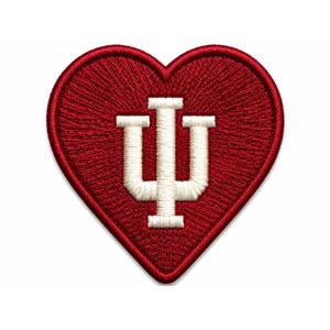Puede incluir: Un parche bordado en forma de corazón con un fondo rojo intenso y el logotipo IU de la Universidad de Indiana bordado en blanco en el centro. El parche tiene un borde rojo grueso y elevado con un acabado de hilo denso y texturizado.