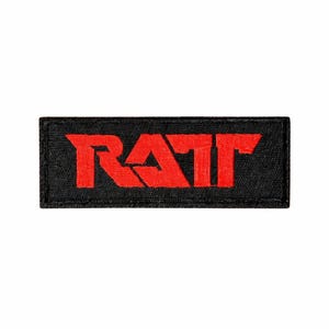 May include: Black rectangular patch with the word "RAW" in bold, red, block letters. The letters are slightly distressed, giving a textured appearance. The patch has a black border and is likely made of fabric.