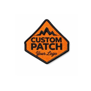 Puede incluir: Parche personalizado naranja en forma de diamante con borde negro. El parche presenta un gráfico de montaña sobre las palabras "CUSTOM PATCH" y "Your Logo" en fuente cursiva. Ideal para logotipos personalizados.